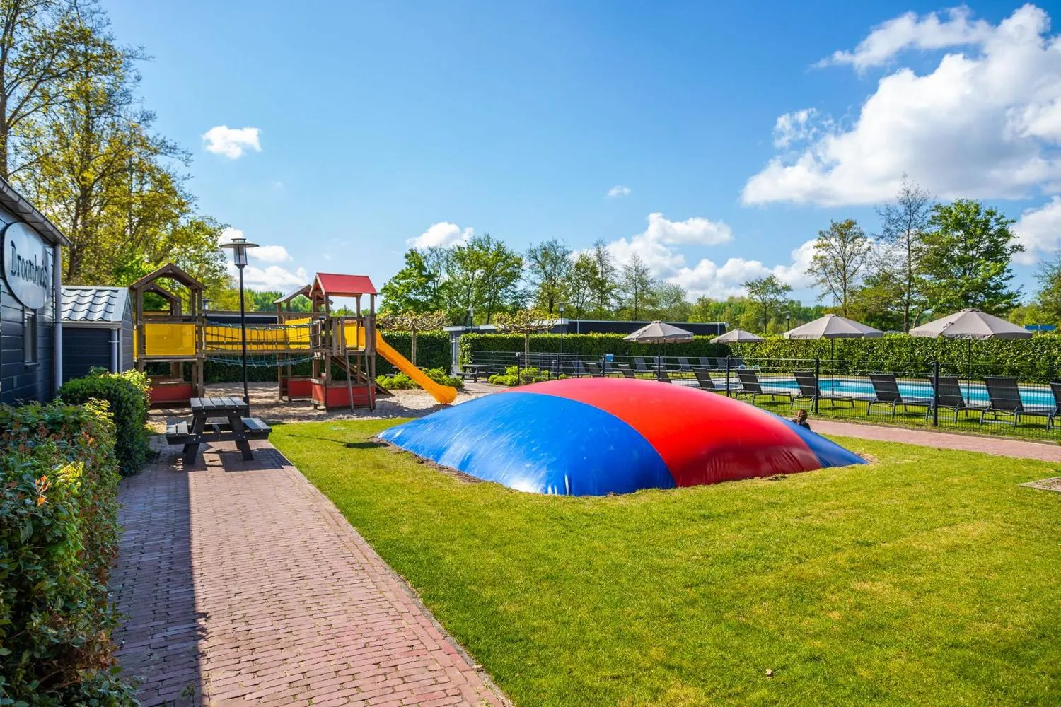 Freizeitanlage mit Trampolin, Spielplatz und Liegestühlen am Pool