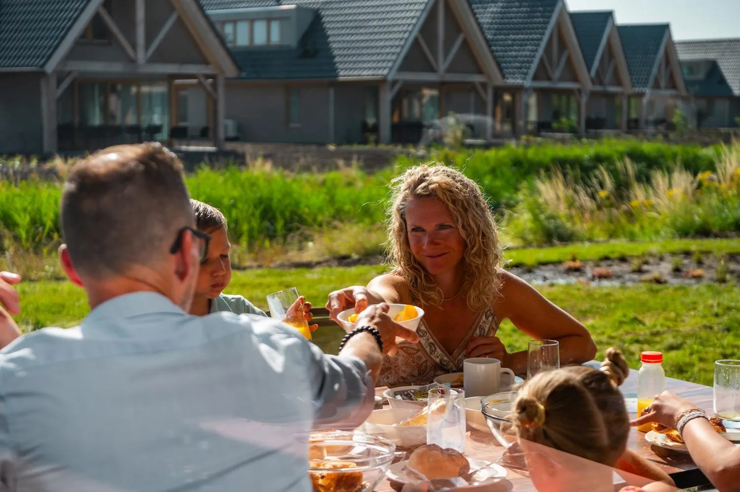Frau und Kinder beim Frühstück draußen vor Ferienhäusern