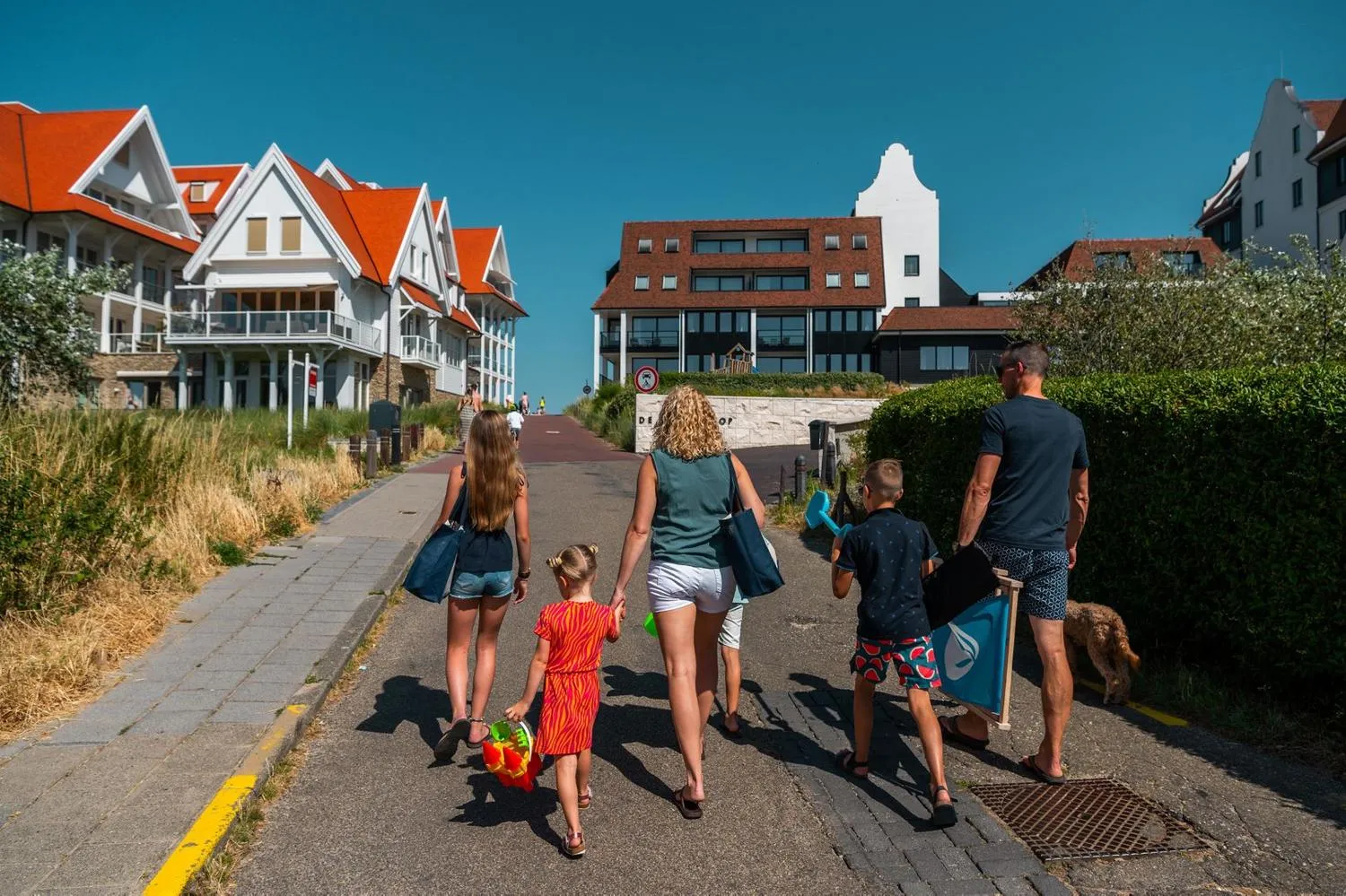 Familie mit Kindern spaziert durch Cadzand-Bad zum Strand