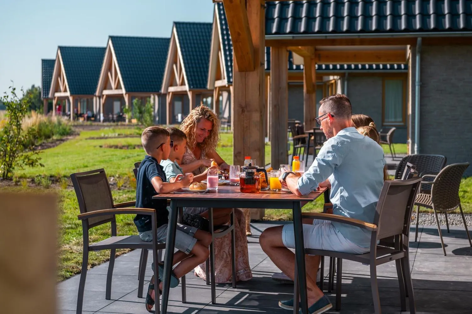 Familie beim Frühstück draußen vor modernen Ferienhäusern