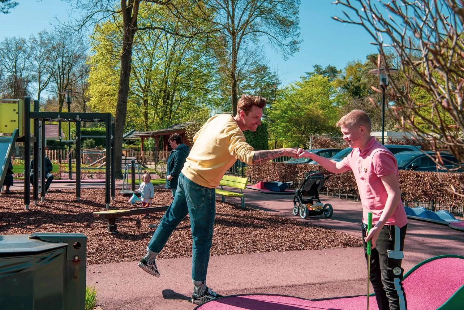 Kinderplatz mit Trampolinen, Rutsche und Klettergerüst auf Holzschnitzel-Untergrund