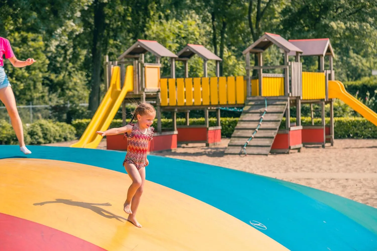 Kind hüpft auf buntem Trampolin-Spielgerät im Außenspielplatz