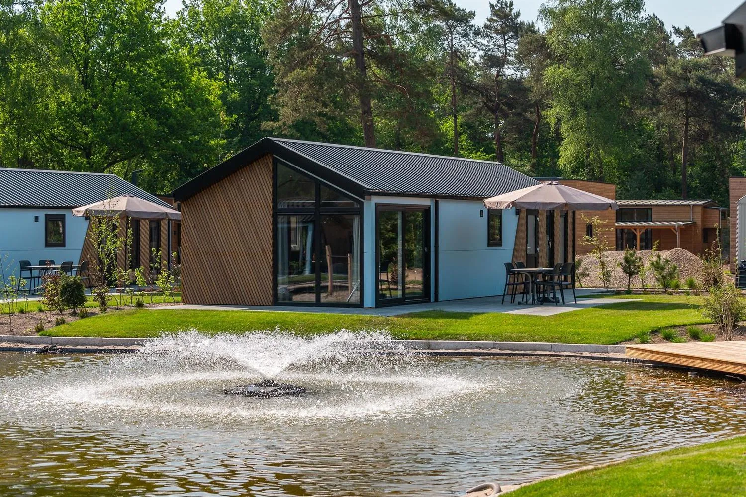 Mehrere moderne Ferienhäuser mit Terrassen um einen See mit Springbrunnen