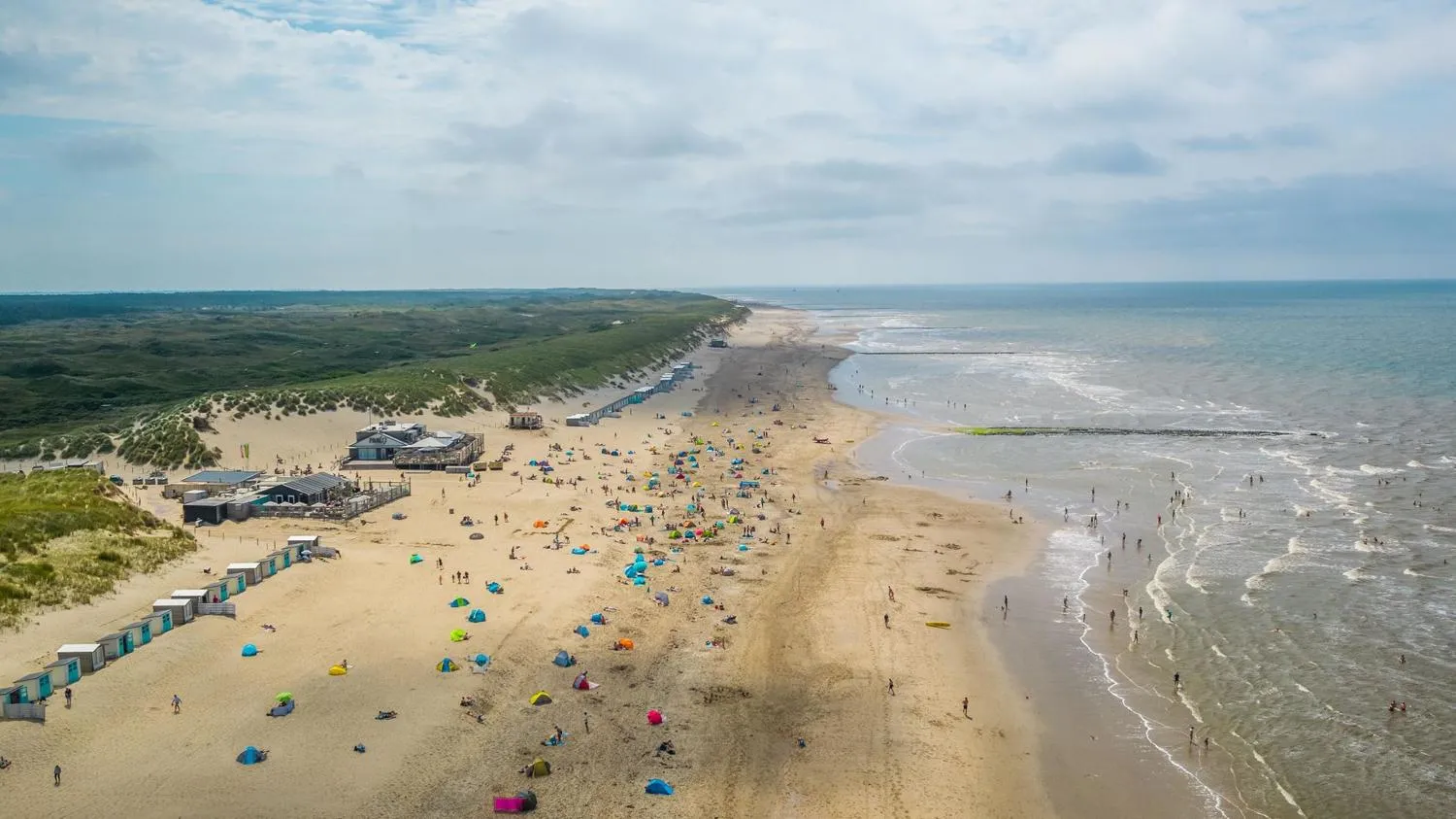 Belebter Nordseestrand mit Badegästen, bunten Zelten und Strandkörben