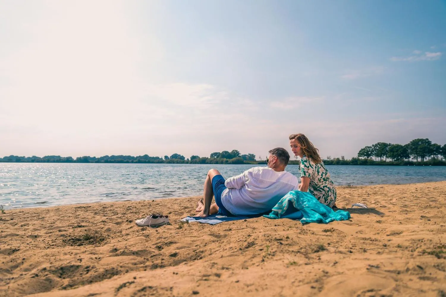 Familie entspannt am Sandstrand mit Blick auf den See