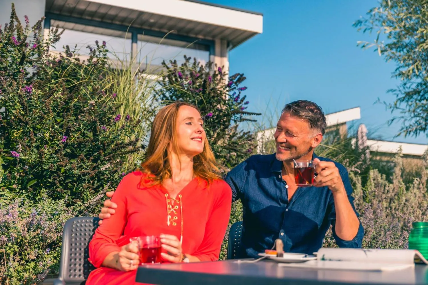 Paar genießt Getränke unter einer modernen Pergola mit Gartenblick