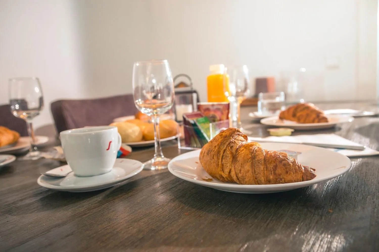 Frühstückstisch mit Croissant, Kaffee und Gläsern