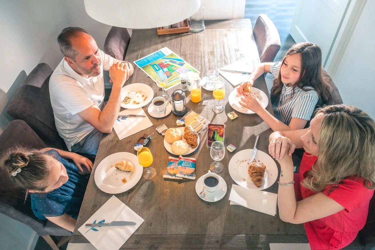 Familie beim Frühstück mit Croissant und Getränken