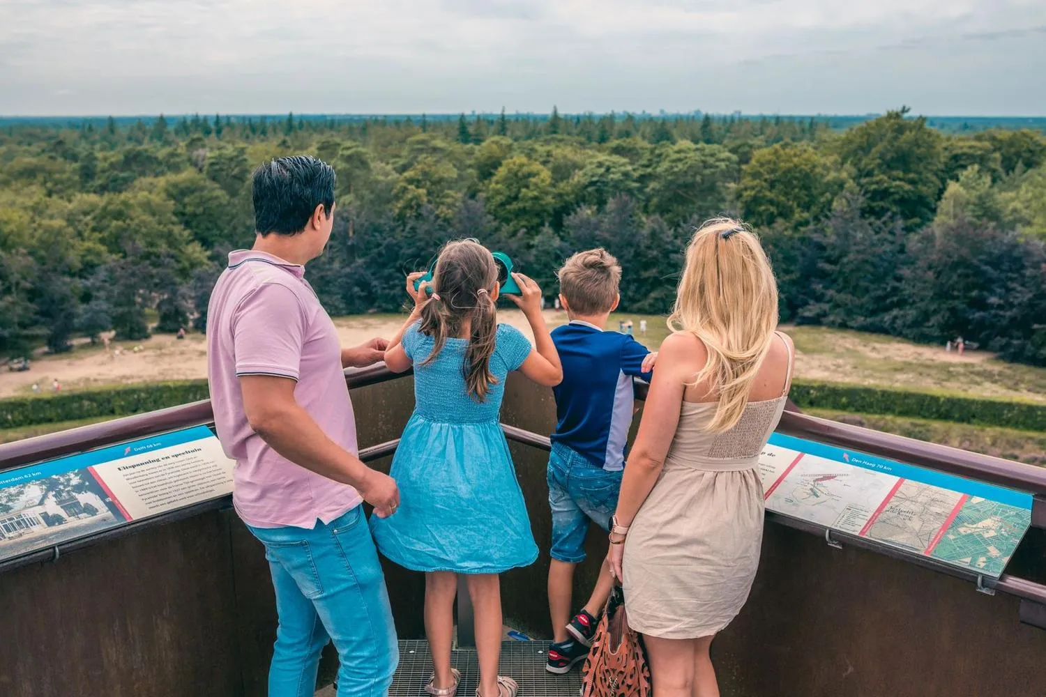 Familie an Aussichtspunkt über ausgedehnte Waldlandschaft