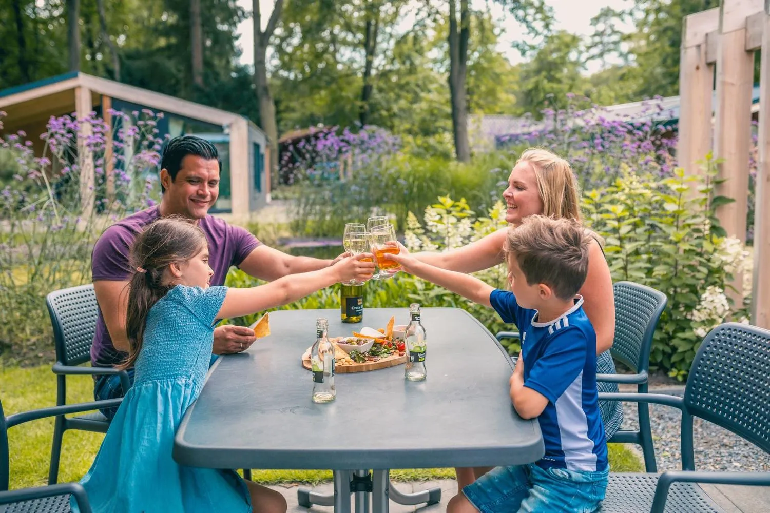 Familie stößt mit Getränken an im Garten mit Lavendelblüten