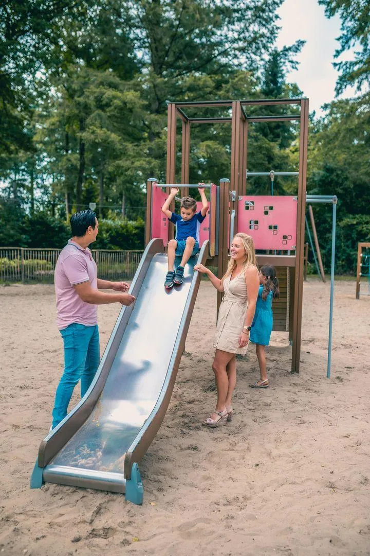 Eltern und Kinder auf Rutsche im Spielplatzbereich