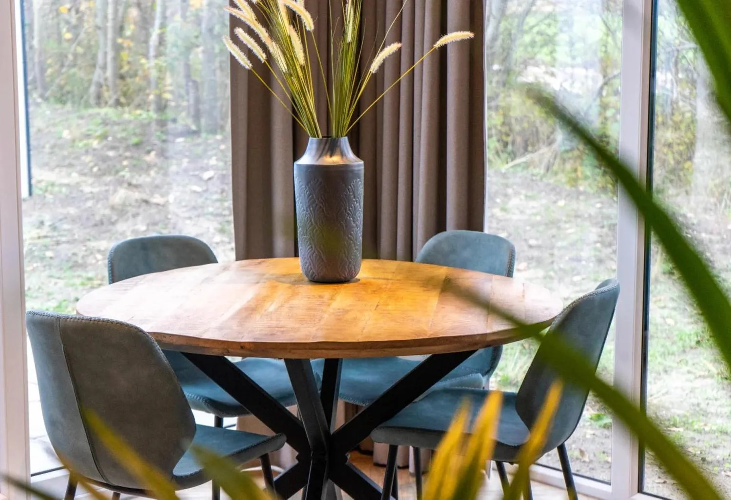 Wohnzimmer mit grauem Sofa, Holztisch und Waldpanorama