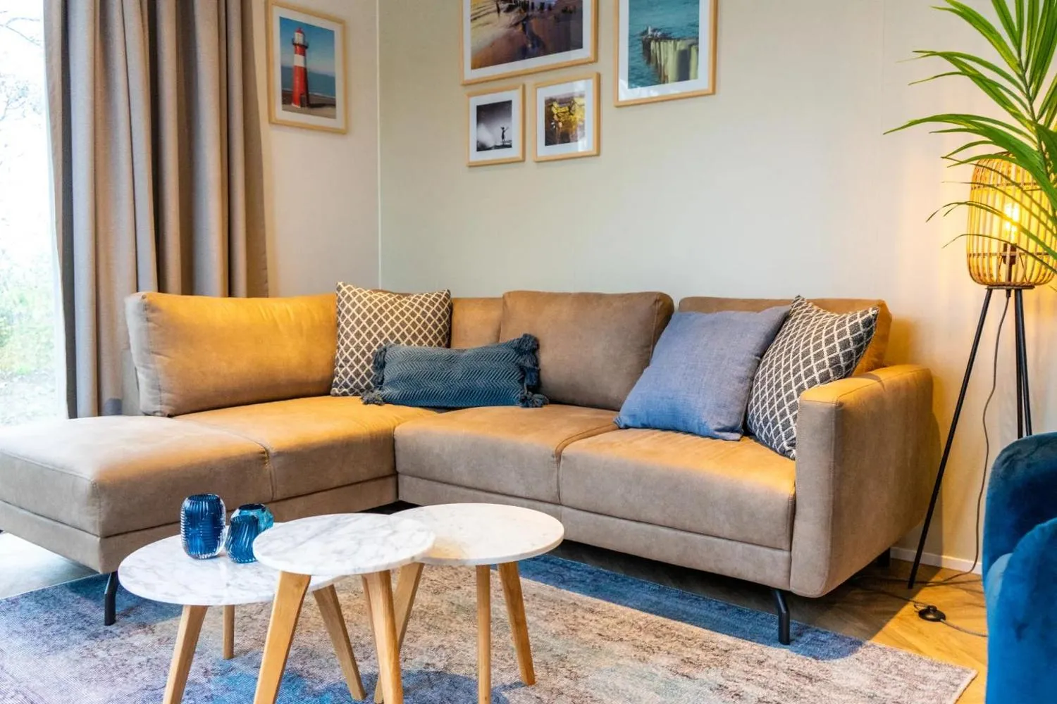 Wohnraum mit grauem Sofa, Holztischen und Waldblick