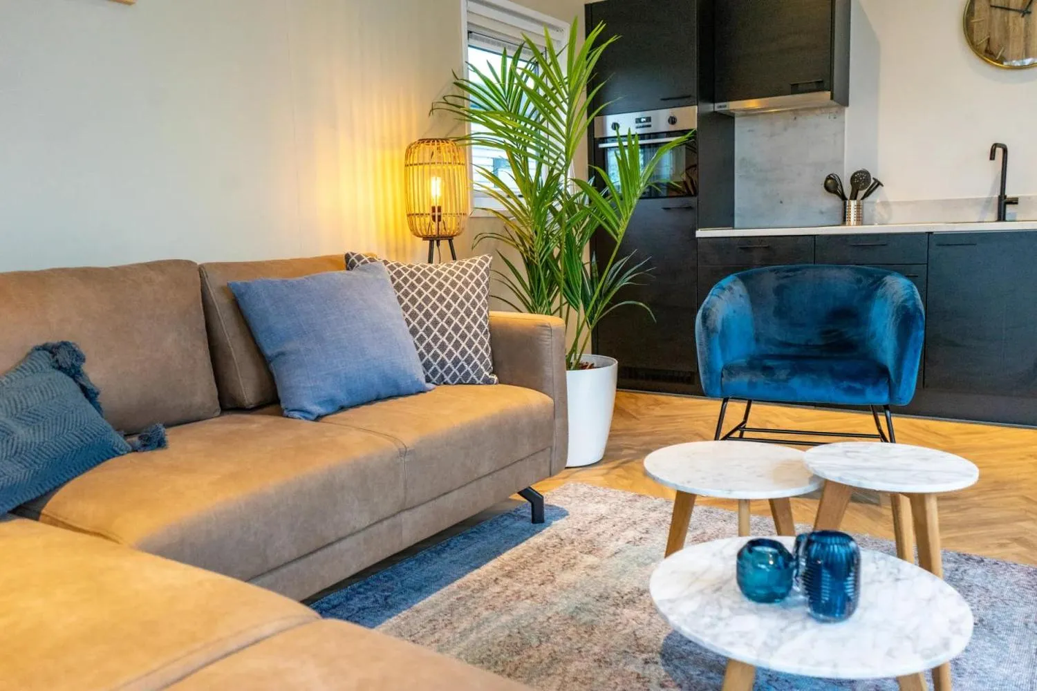 Wohnzimmer mit beiger Couch, blauen Kissen und Wandbildern