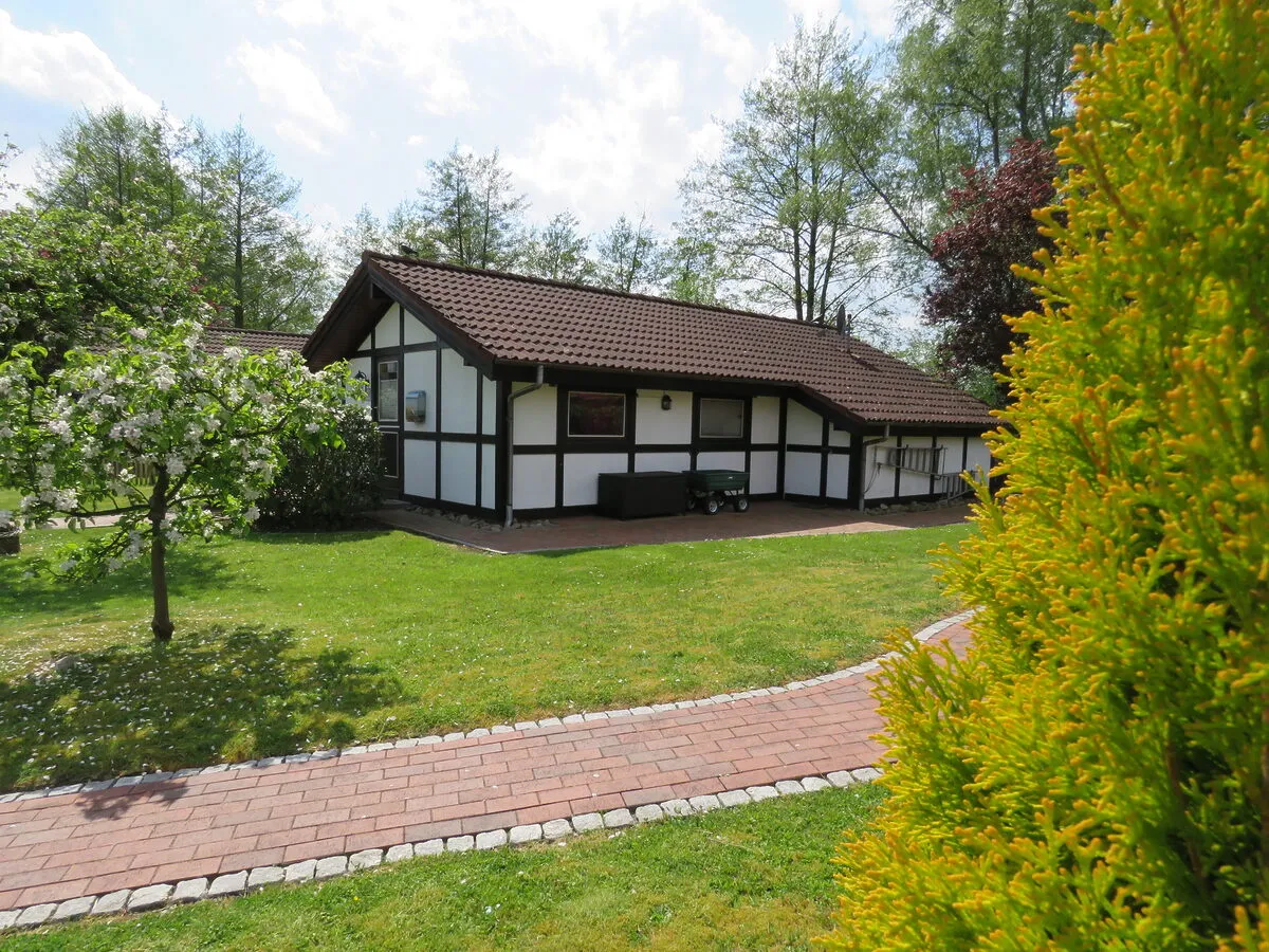 Weißes Fachwerk-Ferienhaus mit Garten und gepflastertem Weg im Feriendorf Altes Land