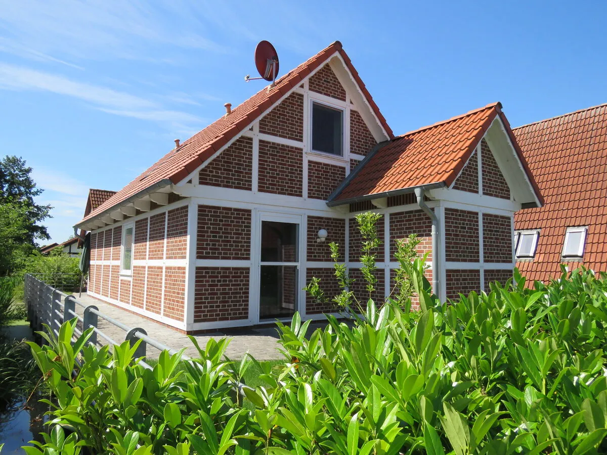 Fachwerk-Ferienhaus mit Terrassentür und Hecke im Feriendorf Altes Land