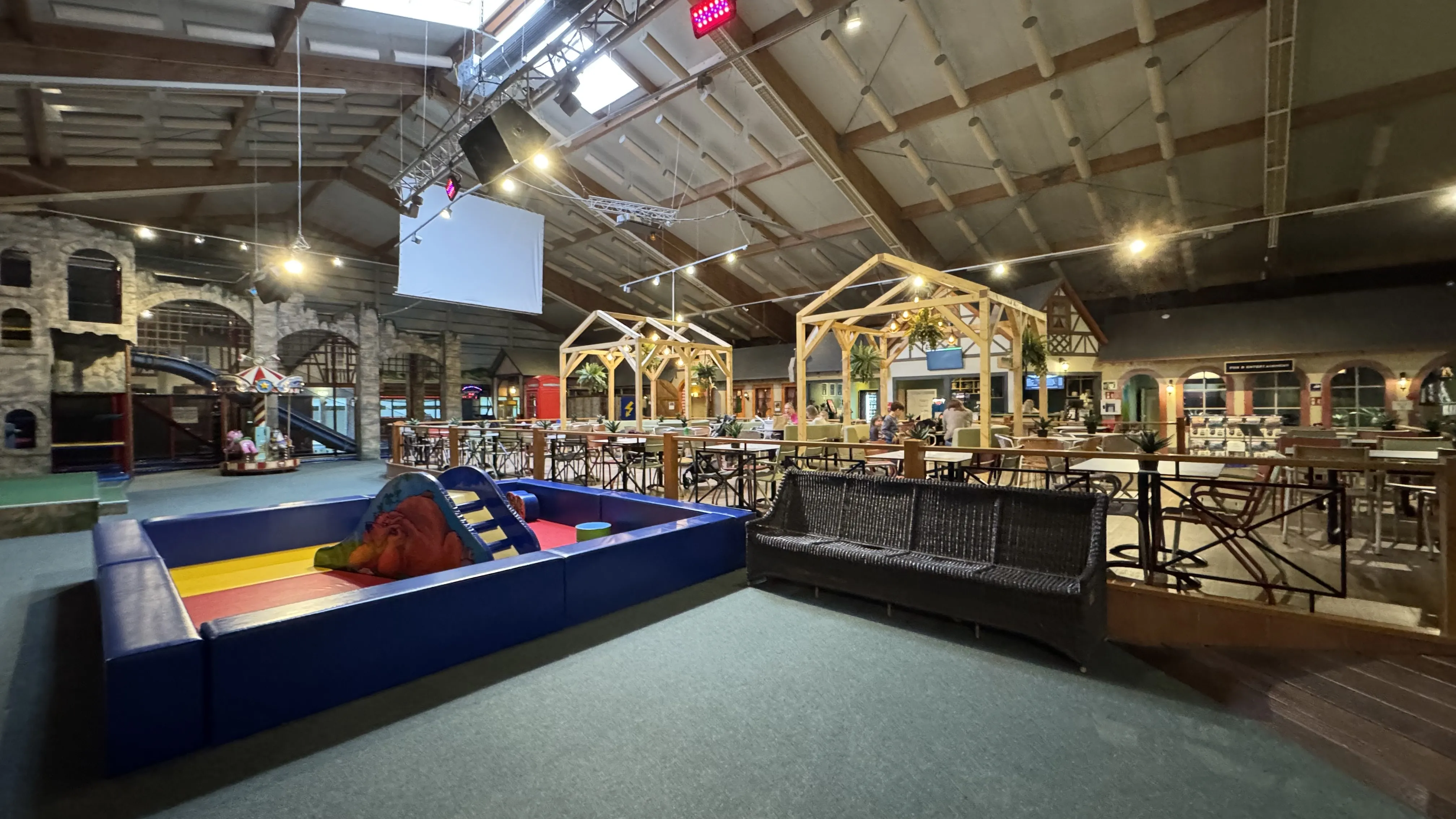 Blick in die Halle des Indoor-Spielparadieses im Landal Sonnenberg mit Sitzbereichen für Eltern