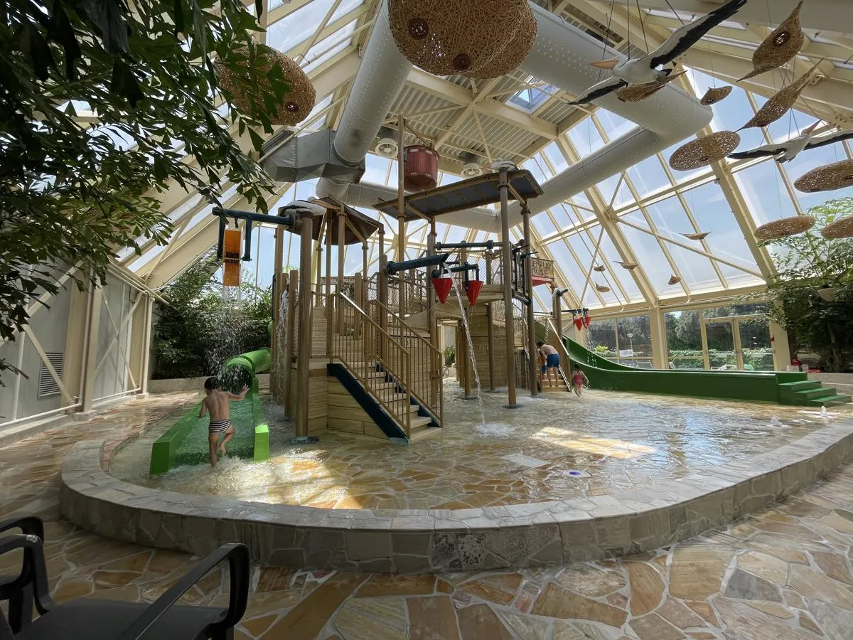 Überdachter Wasserspielplatz mit Rutschen und Kletterelementen für Kinder