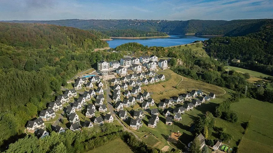 Ferienpark aus der Luft mit hunderten Häusern, See und bewaldeter Eifellandschaft